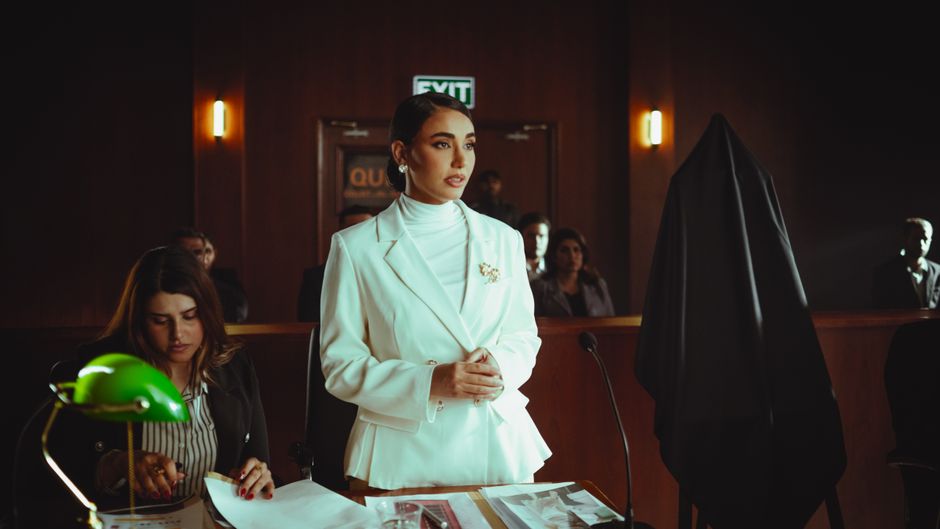 Confident professional woman stands in a courtroom, representing legal authority.