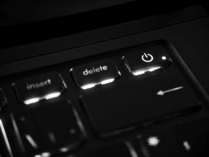 Black and white macro shot of illuminated keyboard keys showcasing delete, insert, power symbols.